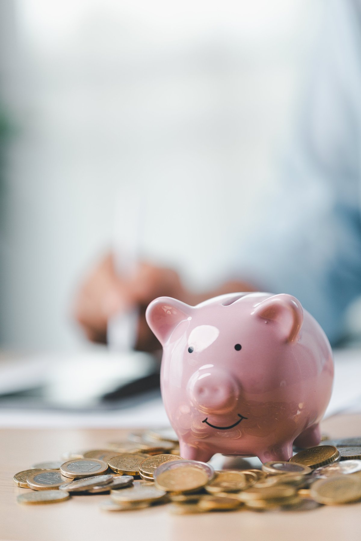 Piggy bank surrounded by coins on a desk, representing saving and financial security